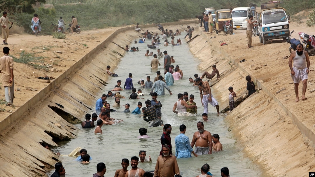FILE - People cool themselves off in a canal as temperature reached 44 C (111 F) in Karachi, Pakistan, May 30, 2018. 