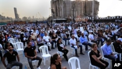 Relatives of victims killed in the massive blast last year at the Beirut port hold their portraits as they attend a Mass held to commemorate the first year anniversary of the tragedy, at the Beirut port, Lebanon, Aug. 4, 2021.