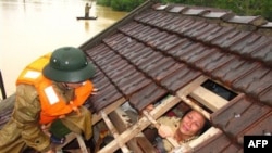 Một phụ nữ rơi nước mắt chờ được cứu ra khỏi ngôi nhà bị ngập ở tỉnh Hà Tĩnh, Việt Nam, ngày 17/10/2010
