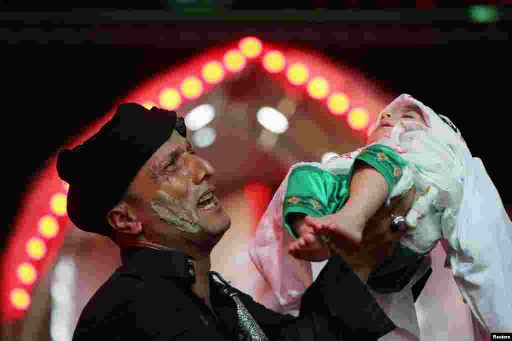 A Shi'ite Muslim holds a child as he takes part in an Ashura procession in the holy city of Kerbala, Iraq.