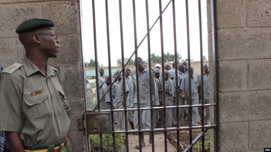 A corrections officer looks on as inmates gather near housing units at Naivasha Maximum Prison in Kenya, October 2014. (Gabe Joselow/VOA) 