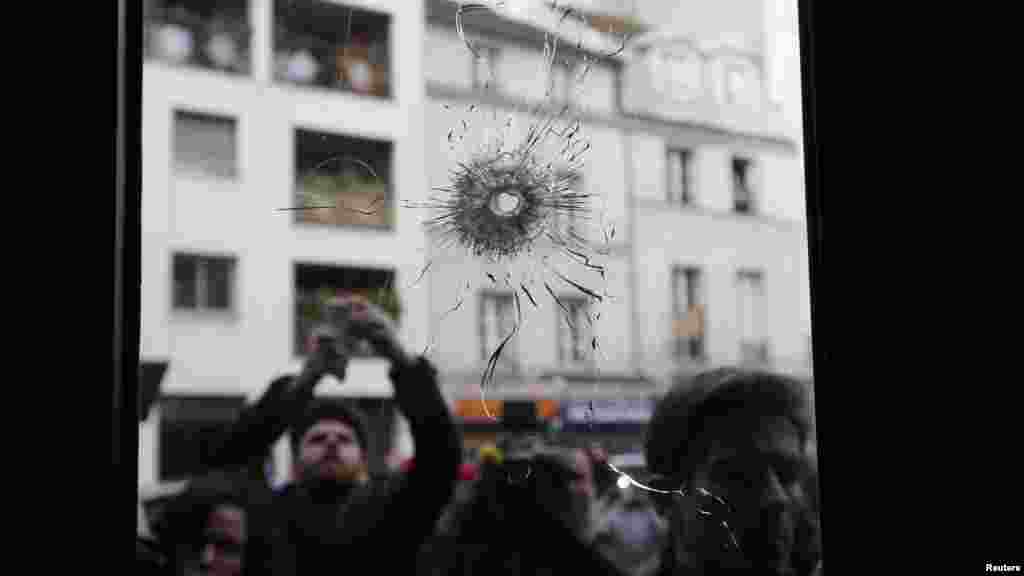 Journalists work outside a restaurant where bullet impacts are seen the day after a series of deadly attacks in Paris, France, Nov. 14, 2015.