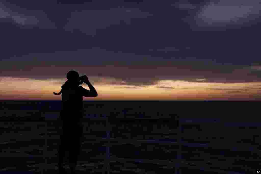 A member of SOS Mediterranee's Search and Rescue team monitors the horizon at dawn with binoculars for potential boats in distress from aboard the Ocean Viking in international waters north of Libya.
