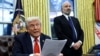 Presidente dos Estados Unidos, Donald Trump, lê sobre as taxas sobre o aço e o alumínio, com Howard Lutnick em segundo plano, no Salão Oval da Casa Branca, em Washington, 10 de fevereiro de 2025
