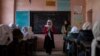 FILE - An Afghan girl reads in a classroom next to her teacher at Tajrobawai Girls High School, in Herat, Afghanistan, Nov. 25, 2021. Schools in Afghanistan are closed to girls beyond sixth grade.