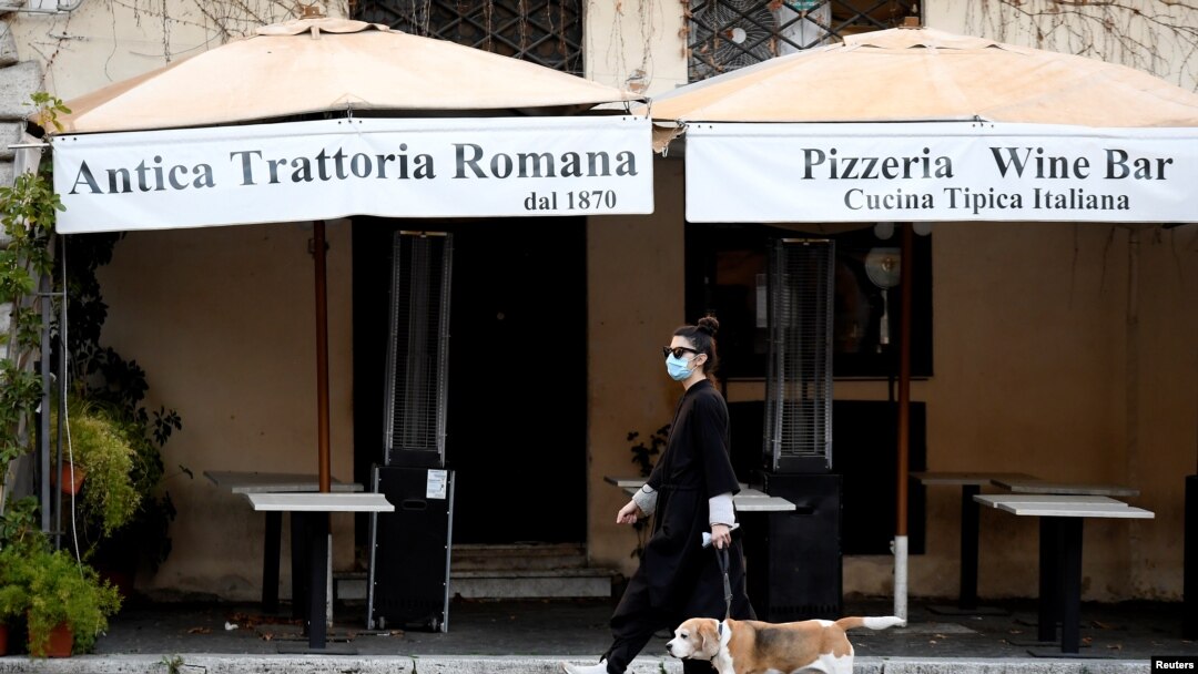 A woman wearing a protective mask walks her dog in Piazza Navona, as Italians remain under lockdown to prevent the spread of the coronavirus disease, in Rome, April 4, 2020.