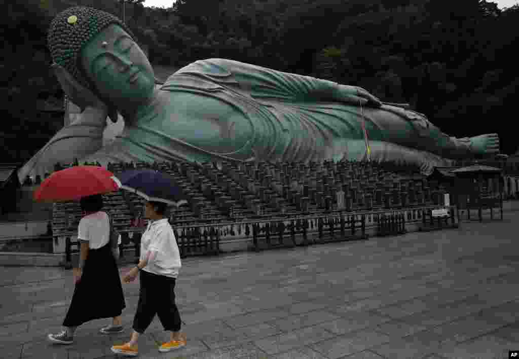 Women walk past the reclining Buddha statue as they visit the Nanzo-in temple in Sasaguri, Fukuoka Prefecture, southwestern Japan. The statue is 41 meters long, 11 meters high, and weighs nearly 300 tons.