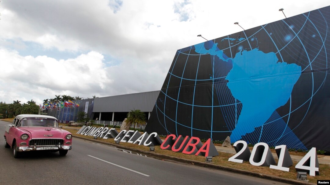 Un auto pasa frente al sitio donde se desarrolla la cumbre de la CELAC, en La Habana.
