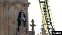 Un hombre con una bandera palestina reacciona junto a los socorristas mientras se encuentra en la Torre Elizabeth, comúnmente conocida como Big Ben, junto a las Casas del Parlamento, en Londres, Gran Bretaña, el 8 de marzo de 2025.