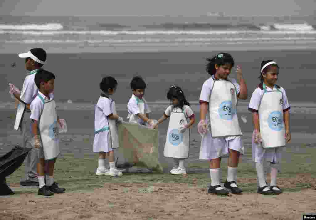 Học sinh Pakestan lượm rác tại bãi biển Clifton ở Karachi vào sáng sớm ngày 21-04-2013 nhân lễ mừng Ngày Trái Đất.
