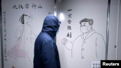 湖北省武漢市雷神山醫院一名工作人員走過中國國家主席習近平戴著口罩的素描海報。該醫院於2020年初武漢爆發Covid-19新冠疫情後火速建成。