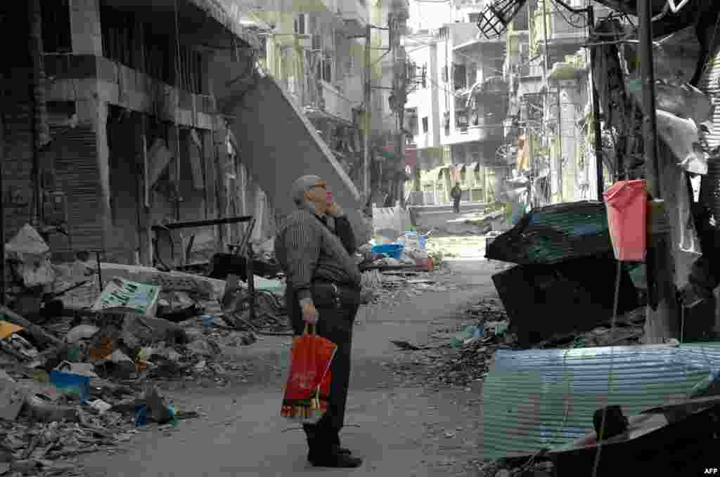 A Syrian resident of Homs looks at a damaged building after returning to the Christian Hamidiyeh neighborhood of the old town of Syria's central city. The last rebels left Homs under an evacuation deal that hands the government a symbolic victory.