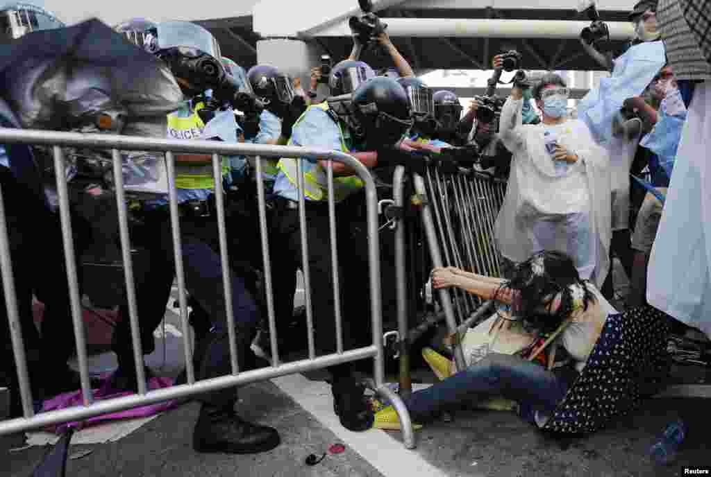 在政府總部大樓外面，警察與民眾發生衝突。一位婦女（右）在和警察的搏鬥中躺在地上，緊緊抓住欄杆。 